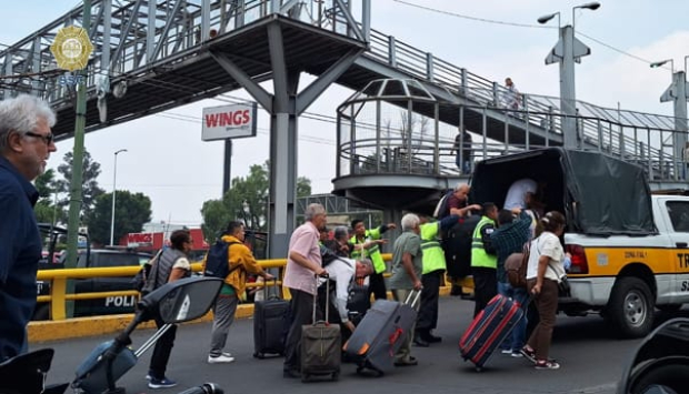 Elementos de la SSC ayudan a pasajeros del Aeropuerto a subir a la parte trasera de camionetas de la institución, en medio del caos.