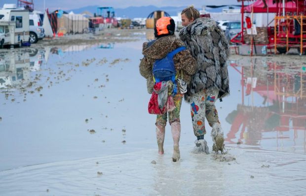 Asistentes a Burning Man caminan en el barro que se formó por las fuertes lluvias.