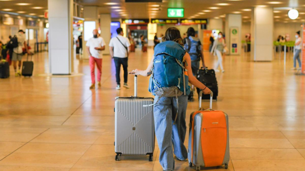 Turista de niña en el aeropuerto lleva una maleta con ruedas con una bolsa.  concepto sobre el tema del turismo.