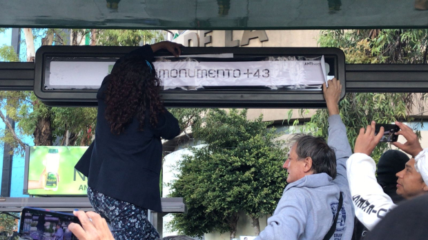 Una persona coloca un letrero con la leyenda "Monumento+ 43"