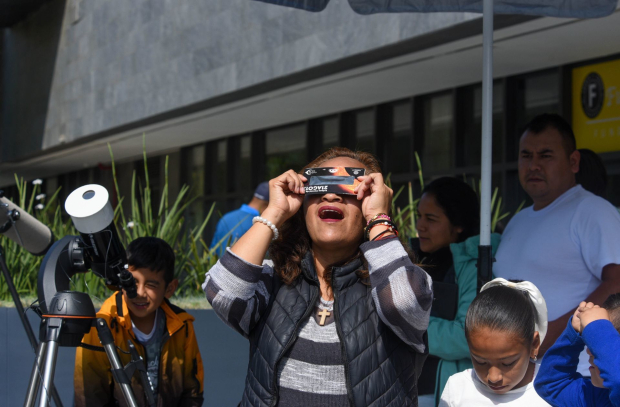 En Toluca, una familia observa el eclipse con lentes especiales.