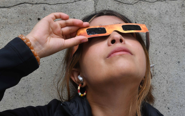 Una joven aprecia el eclipse solar desde el Ángel de la Independencia, Ciudad de México.