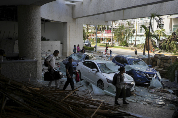 Turistas abandonan uno de los hoteles afectados por el meteoro.