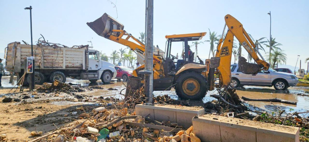 Con apoyo de una excavadora, trabajadores de Guerrero recogen los escombros y basura, ayer.