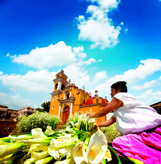 Una mujer vendiendo flores afuera  de la parroquia, en Xalapa.