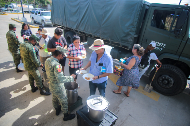 Elementos del Ejército entregan platos de guisados calientes para los afectados.