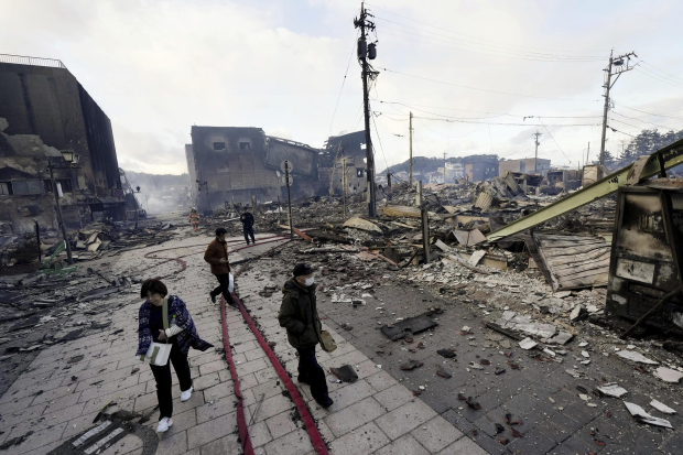 Residentes caminan en medio de escombros, un día después del terrible terremoto.