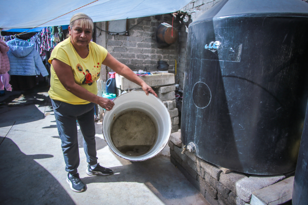 Una mujer muestra un tambo semivacío y con agua sucia, debido a las polvaredas.