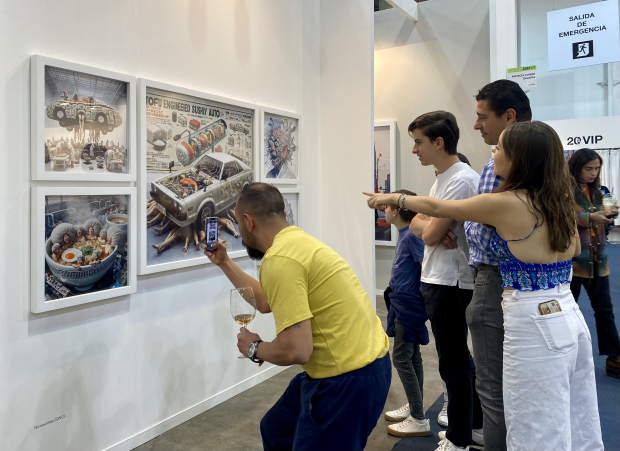 Un asistente toma una foto de las imágenes de la galería Patricia Conde.