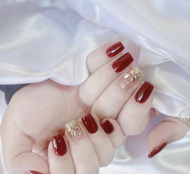 Las uñas rojo con dorado pueden lucir hermosas con brillos.