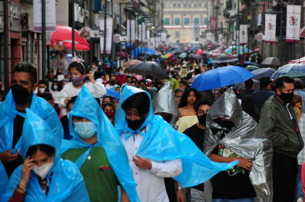 Decenas de personas caminan por la calle de Madero mientras se protegen de la lluvia con paraguas y plásticos. Archivo.