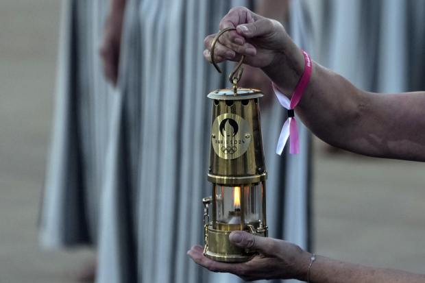 Un miembro del comité organizador de los Juegos de París 2024 sostiene la linterna con el fuego de los Juegos Olímpicos