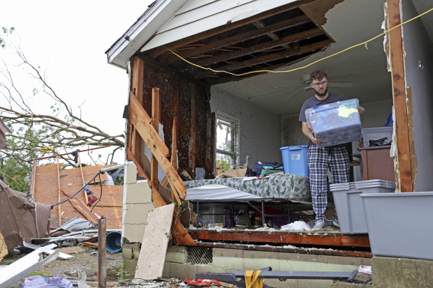 Un residente recupera algunos objetos en una casa golpeada por el tornado, pues se quedó sin una pared, ayer.