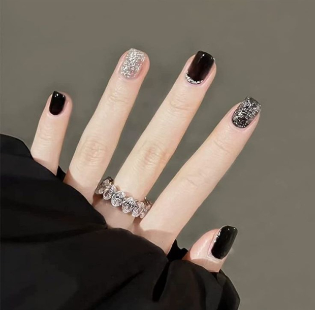 Diseño de uñas cortas negras con brillitos.