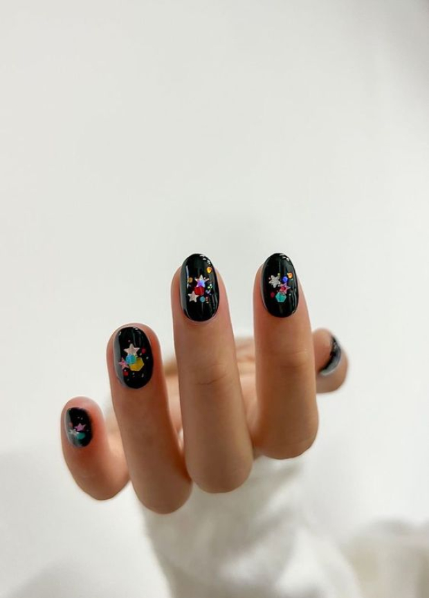 Diseño de uñas cortas negras con brillitos.