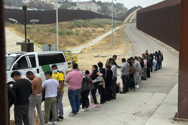 Migrantes que buscan asilo se forman mientras esperan a ser procesados en la zona fronteriza de San Diego, California, el 5 de junio.