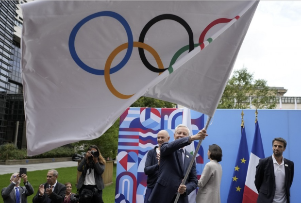 El ministro de Finanzas francés, Bruno Le Maire, ondea la bandera olímpica en París