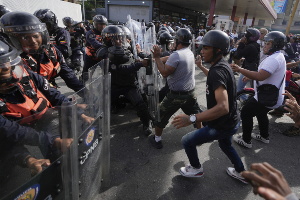 Manifestantes chocan con policías en calles de Venezuela en rechazo a la nueva reelección de Nicolás Maduro, ayer.