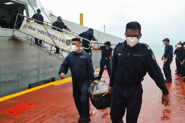 Personal naval transporta para su inspección los costalillos decomisados.