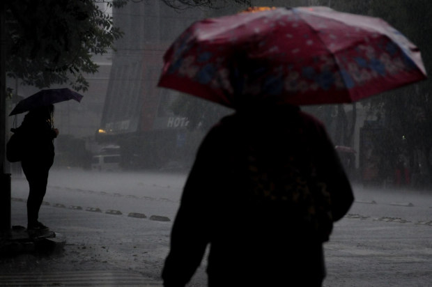 Dos personas caminan bajo la lluvia en la capital.