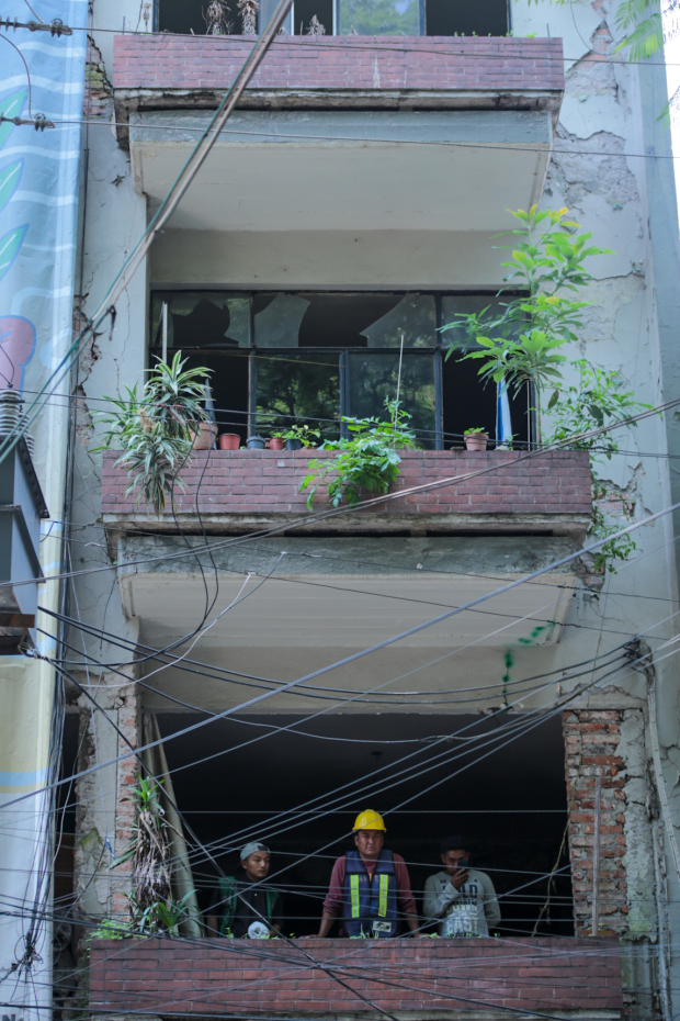 Trabajadores miran a la calle desde el balcón de un apartamento de un inmueble abandonado de la calle Chilpancingo.