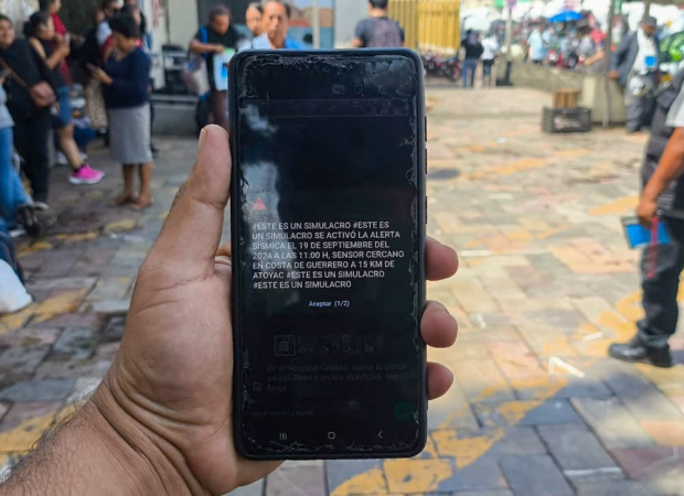 Un hombre muestra el mensaje que le llegó a su teléfono celular, ayer, durante el simulacro en la Ciuda de México.