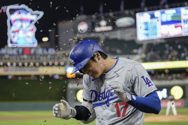 El bateador designado de Los Ángeles, Dodgers, Shohei Ohtani, es rociado con semillas de girasol después de conectar un jonrón solitario durante el partido contra los Mellizos de Minnesota