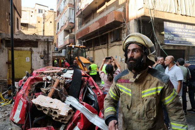 Bomberos responden a nuevos bombardeos en Beirut, ayer, que destruyeron autos y varios inmuebles.