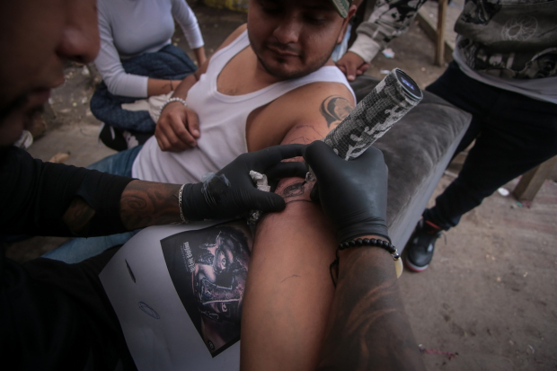 Un hombre se hace un tatuaje de un hombre con casco espartano.