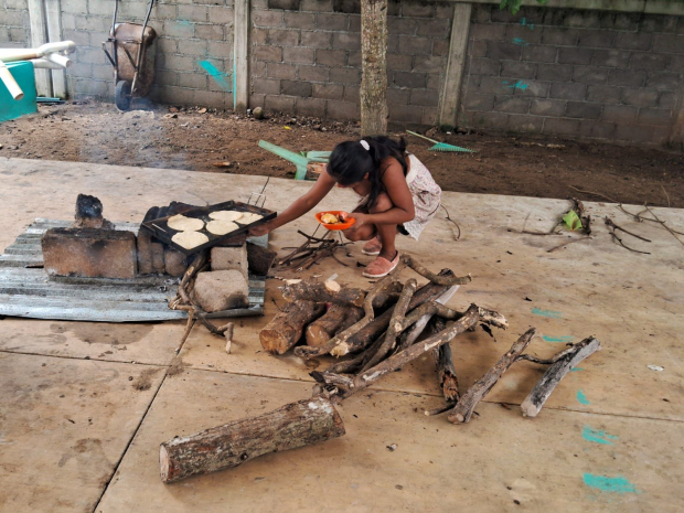 Una joven madre calienta unas tortillas en un refugio de Banco de Oro.