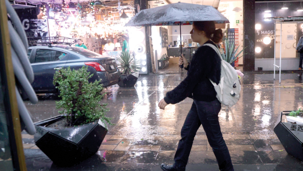 Una mujer se cubre de la lluvia con un paraguas, mientras camina por las calles de la Ciudad de México.