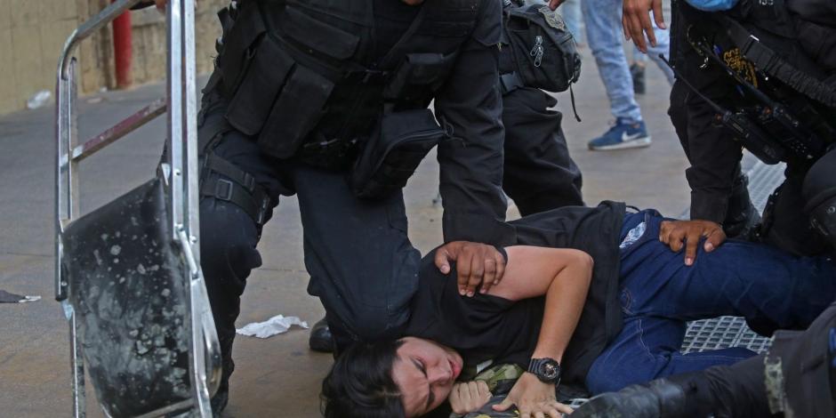 Policías someten a un manifestante afuera del Palacio de Gobierno