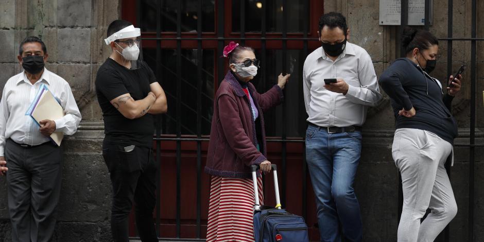 Personas con cubrebocas hacen fila antes de ingresar a un banco, el 6 de julio de 2020, en el centro de la Ciudad de México.