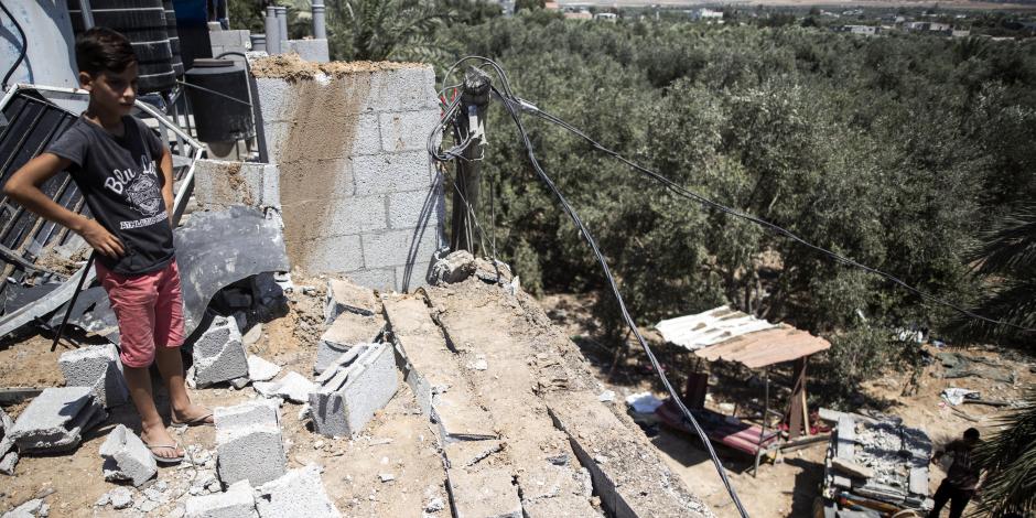 Un chico palestino inspecciona los daños causados a la casa de su familia después de un ataque aéreos israelí en el campamento de refugiados de Buriej, en el centro de la Franja de Gaza, el sábado 15 de agosto de 2020. (AP Foto/Khalil Hamra)