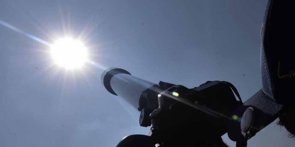 Estudiantes observan el sol con telescopios.