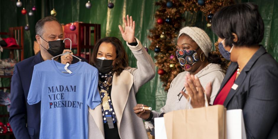 La vicepresidenta electa, Kamala Harris, acompañada por su esposo, Doug Emhoff, sostiene una camiseta, en un puesto en el Holiday Market, el 28 de noviembre de 2020, en Washington.