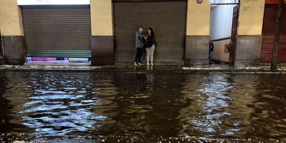 Dos personas se resguardan de la fuerte lluvia acompañada de granizo que se registró anoche en la Ciudad de México.