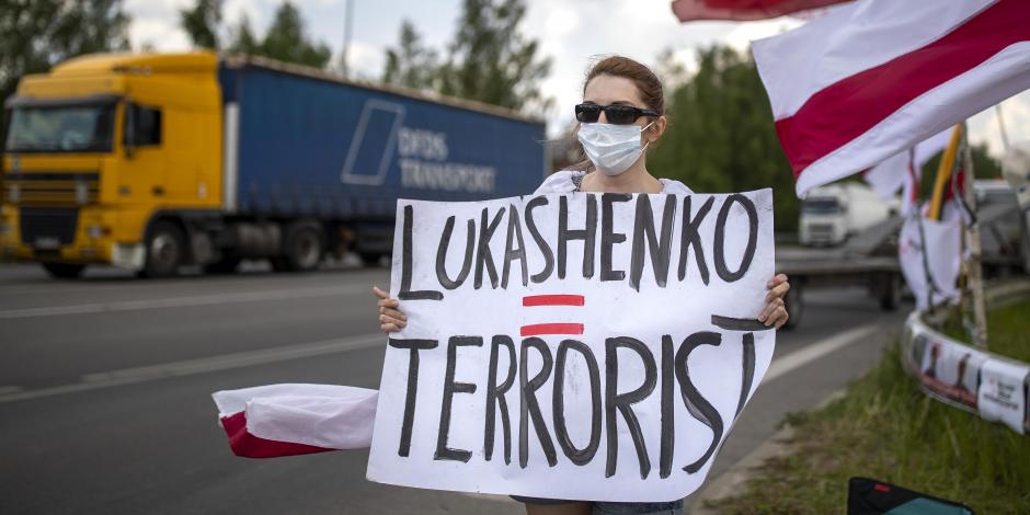 Una manifestante lleva un cartel que dice "Lukashenko = Terrorista" en una protesta contra el presidente bielorruso.