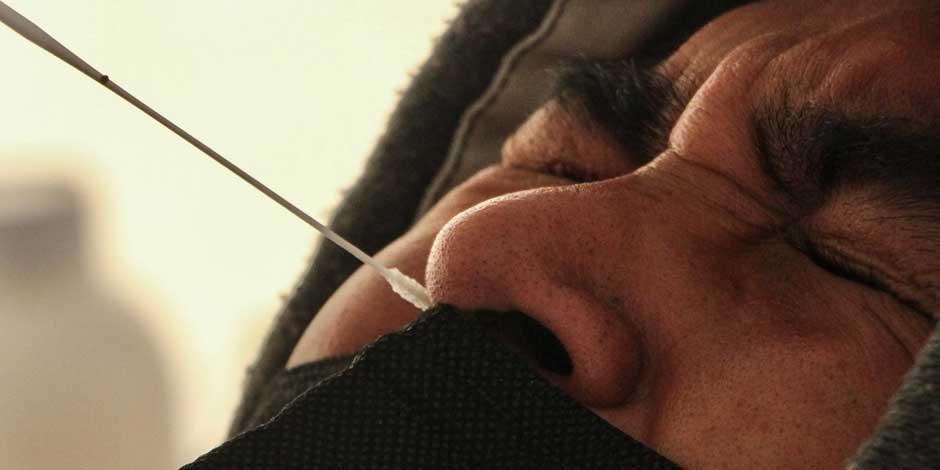 Un adolescente aprieta los ojos durante una toma nasal para la detección de coronavirus