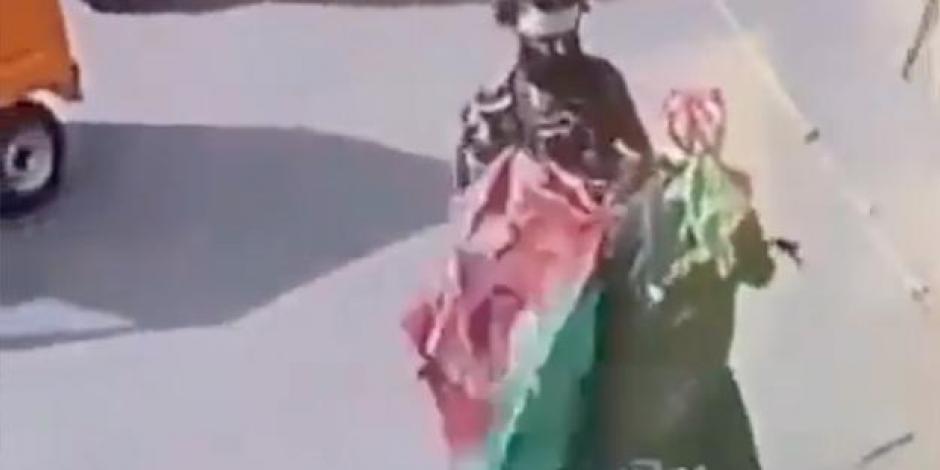 Un sujeto vestido de militar arrebata una bandera afgana a un ciclista.