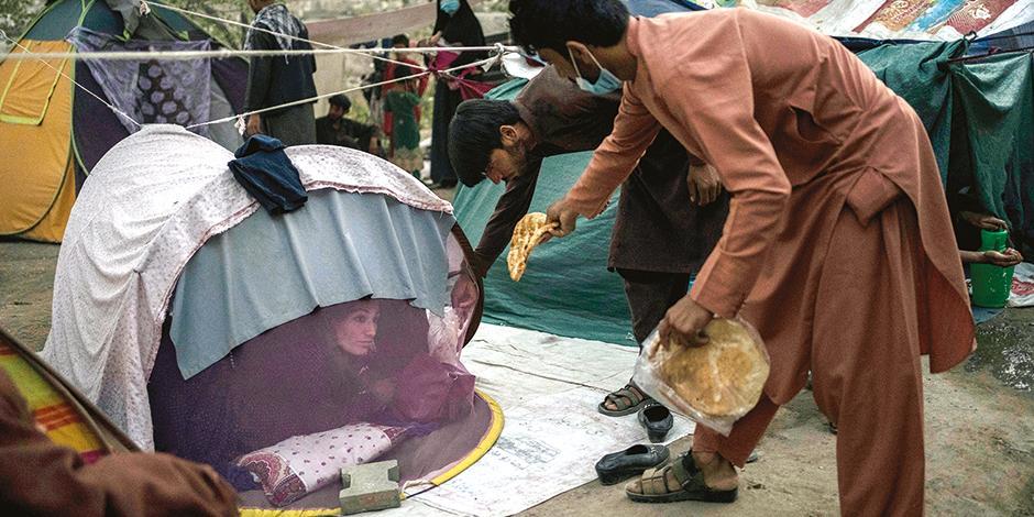 Afganos desplazados comparten ayuda humanitaria en campamentos en Kabul, ayer.