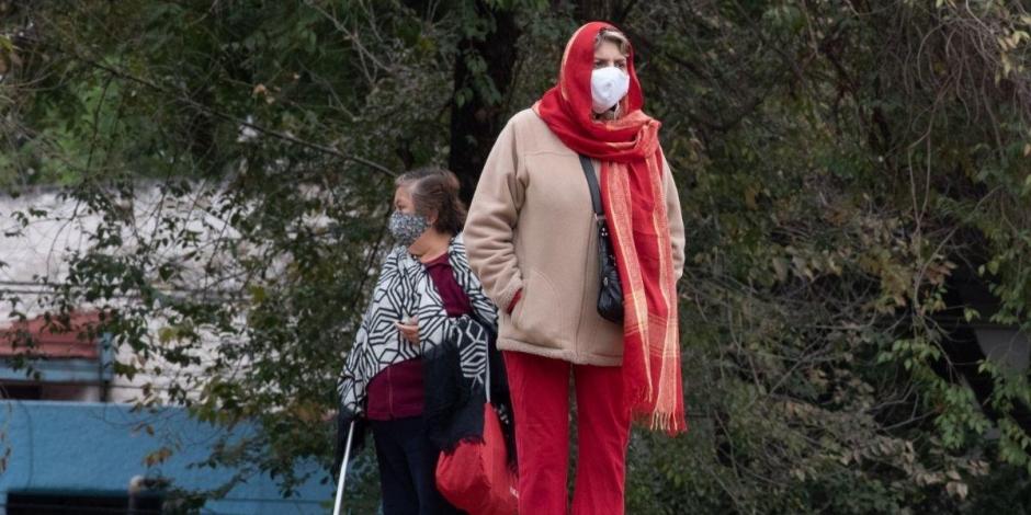 Dos mujeres se cubren del frío en calles de la CDMX ante bajas temperaturas.
