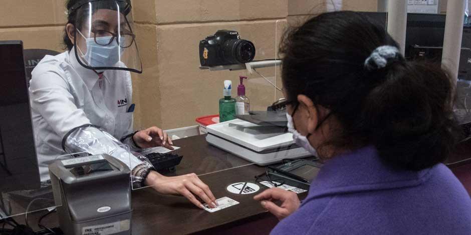 Empleada en módulo del INE entrega credencial de elector a una ciudadana