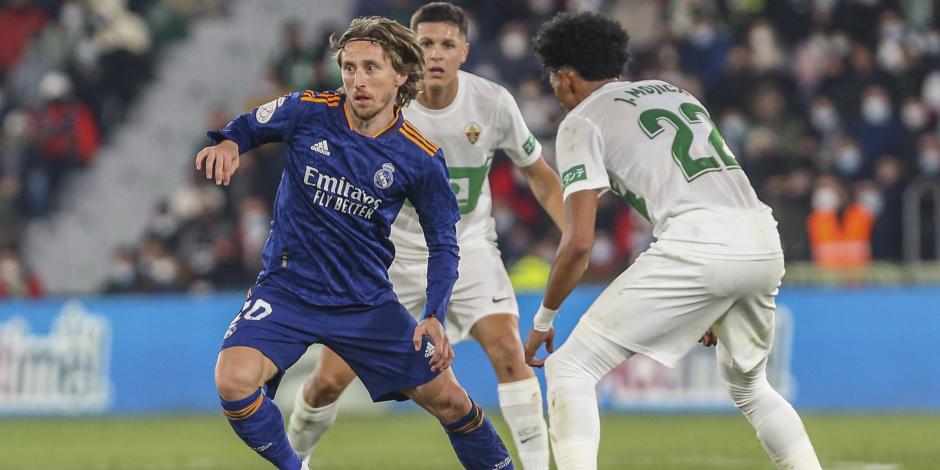 Luka Modric, mediocampista del Real Madrid, conduce el balón entre dos jugadores del Elche en duelo de la Copa del Rey.