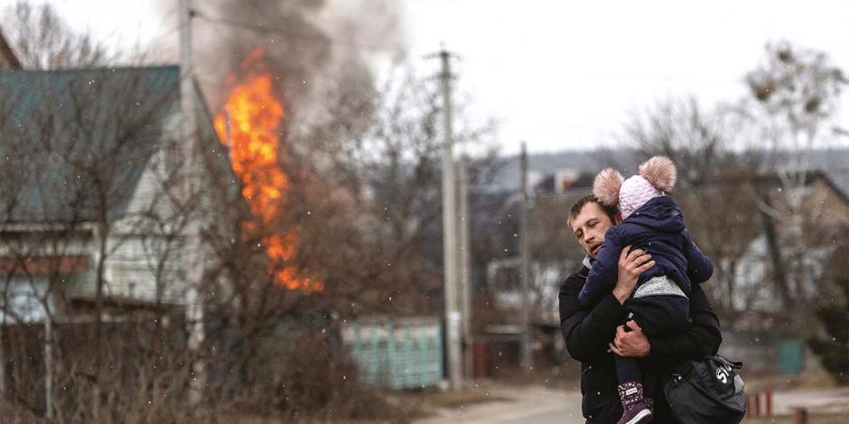 Un hombre camina en busca de ayuda con su hijo en brazos, luego de un bombardeo en su ciudad.