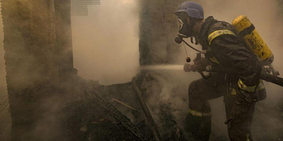 Un bombero ucraniano rocía agua dentro de una casa destruida por los bombardeos, en Kiev, Ucrania.