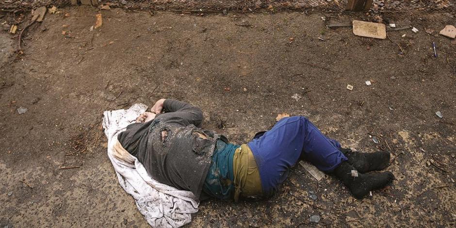Ciudadanos observan cuerpos apilados en una fosa en Bucha.