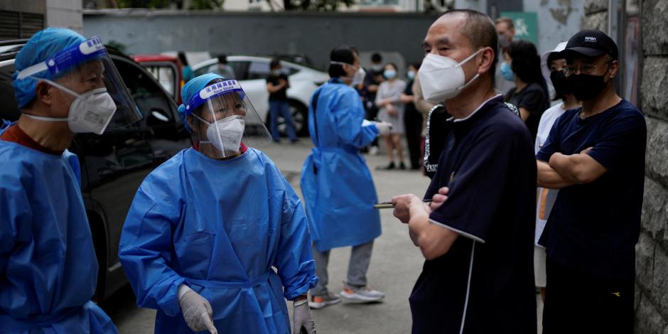 Trabajadores con trajes protectores dirigen a los residentes que hacen fila para hacerse pruebas de COVID-19, en medio de nuevas medidas para frenar el brote de la enfermedad en Shanghái, China
