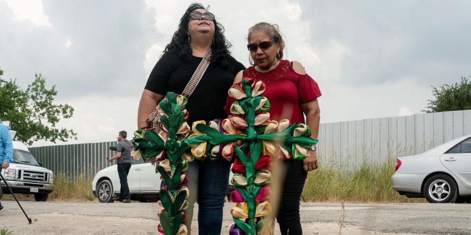 Personas lloran después de colocar cruces y velas en el lugar donde decenas de personas fueron encontradas muertas dentro de un tráiler en San Antonio, Texas.