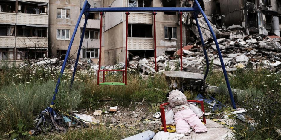 Un oso de peluche y un columpio, junto a edificios destruidos por ataques militares, mientras continúa la invasión rusa a Ucrania
